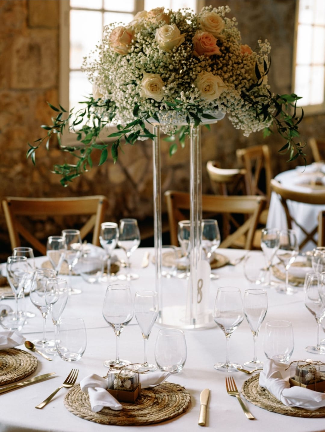 Table ronde de mariage ornée d’un centre fleuri de roses et gypsophile